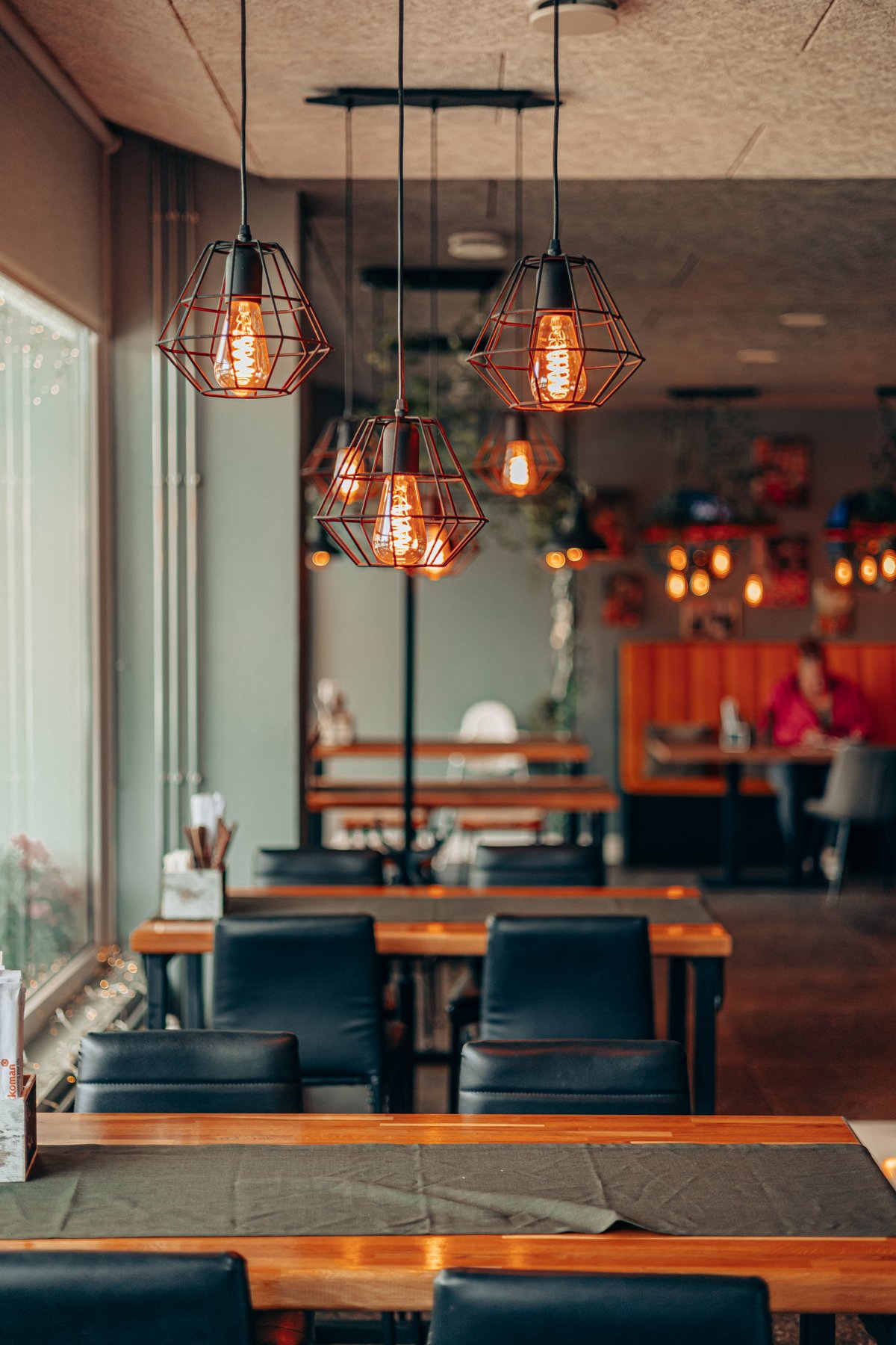 Warm, candlelit restaurant interior with wooden tables and glowing Edison bulbs